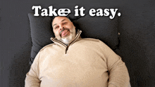 a man is laying on a bed with the words take it easy written above him