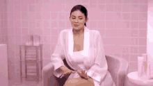 a woman in a pink robe is holding a bottle in her hands .