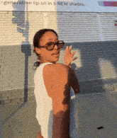a woman wearing sunglasses stands in front of a brick wall