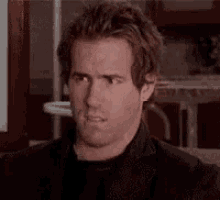 a man with a beard is making a funny face while sitting in a chair .