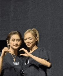two women making a heart shape with their hands