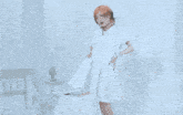 a woman wearing a white dress and a necklace is sitting on a white surface