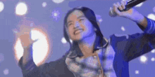 a woman is singing into a microphone with her arms outstretched .