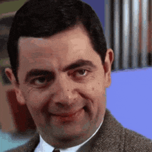 mr bean is making a funny face while wearing a suit and tie .