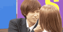 a man in a suit and tie is touching a girl 's face