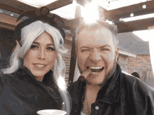 a man with a cigar in his mouth is standing next to a woman in a storm costume