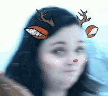 a close up of a woman 's face with reindeer antlers on it