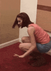 a woman squatting on a red carpet with her hands on the floor