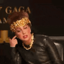 lady gaga is wearing a black leather jacket and a gold headpiece .