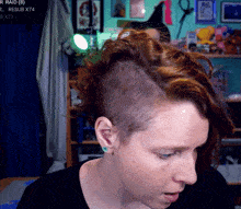 a woman with red hair has a shaved head in front of a screen that says raid