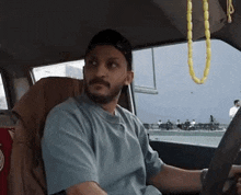 a man is sitting in the driver 's seat of a car and looking at the camera .