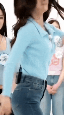 a woman in a blue shirt and blue jeans is dancing in front of a group of people .