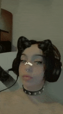 a woman wearing headphones and a choker is taking a picture of herself .