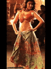 a woman in a crop top and a green skirt is dancing