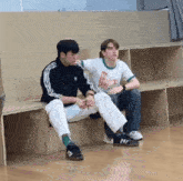 two young men sit on a bench with one wearing a t-shirt that says " runners for fun "