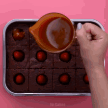 a person is pouring caramel into a pan of brownies with strawberries in them