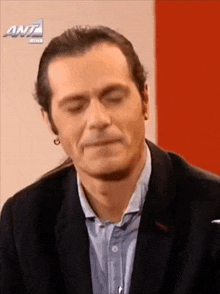 a man in a suit is making a funny face in front of a sign that says ant