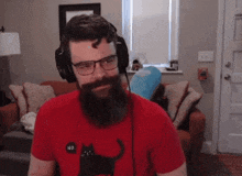 a man with a beard is wearing headphones and a red shirt .