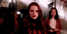 a woman with red hair is standing next to a group of women in a room .