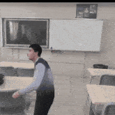 a man in a classroom with a white board and a tv