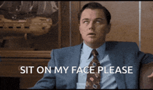 a man in a suit and tie is asking to sit on his face please
