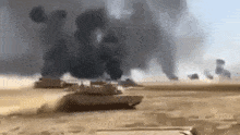 a group of tanks driving through a desert with smoke coming out of them .