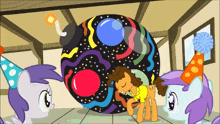 three ponies wearing party hats are standing around a colorful ball