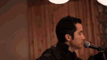 a man is singing into a microphone and his eyes are closed