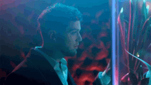 a man in a suit looks out a window at a fish tank