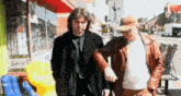 two men are walking down a street in front of a store that says light