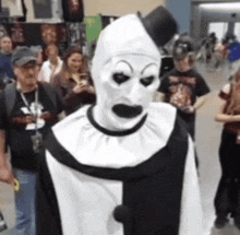 a man in a black and white clown costume stands in a crowd of people