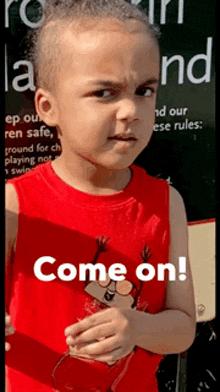 a young boy wearing a red tank top with the words come on written on it