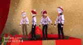 a group of anime characters wearing santa hats are standing on a podium
