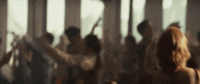a crowd of people are dancing in a room with lots of windows