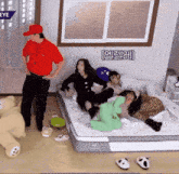 a man in a red shirt stands next to a group of people on a bed with the word eye on the wall