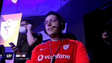a man wearing headphones and a red shirt with the word vodafone on it
