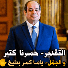 a man in a blue suit and tie stands in front of a sign with arabic writing