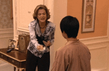 a woman in a floral shirt is talking to a young man