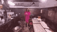 a woman in a pink dress is standing in an empty room .