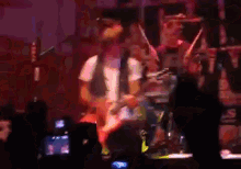 a man playing a guitar on stage with a drummer in the background