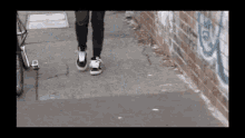 a person walking down a sidewalk with a brick wall behind them