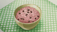 a bowl of pink rice with black beans on a green and white flowered cloth