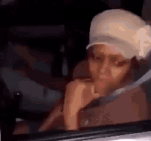 a woman wearing a baseball cap is sitting in a car .