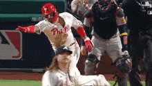a baseball player wearing a phillies jersey is running towards a base