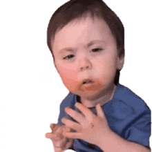 a baby in a blue shirt is making a funny face with chocolate on his face .