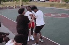 a group of people are standing on a basketball court fighting