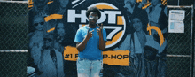 a man wearing sunglasses stands in front of a hot 97 sign
