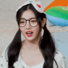 a woman wearing glasses and pigtails is standing in front of a beach ball
