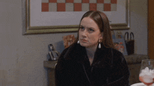 a woman in a fur coat sits at a table