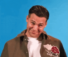 a man wearing a brown jacket with a rose on it makes a funny face